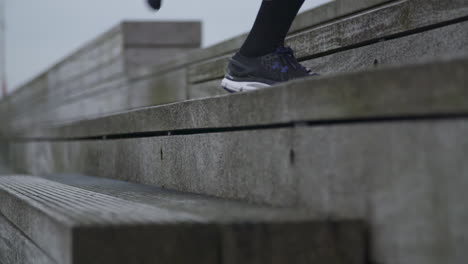 close up of a persons sneakers running up the stairs, in super slow motion. shot outside at daytime during a cloudy day.