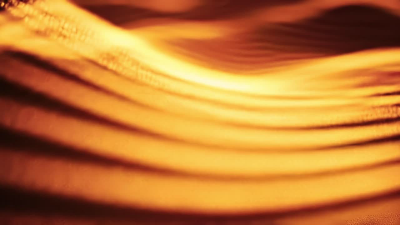 A series of undulating gold waves dance in a warm setting, producing captivating light patterns that evoke a sense of tranquility and wonder.