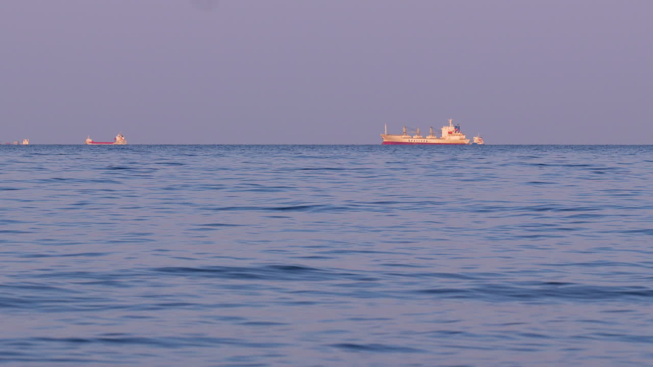 Cargo ship sailing on calm blue sea under evening light