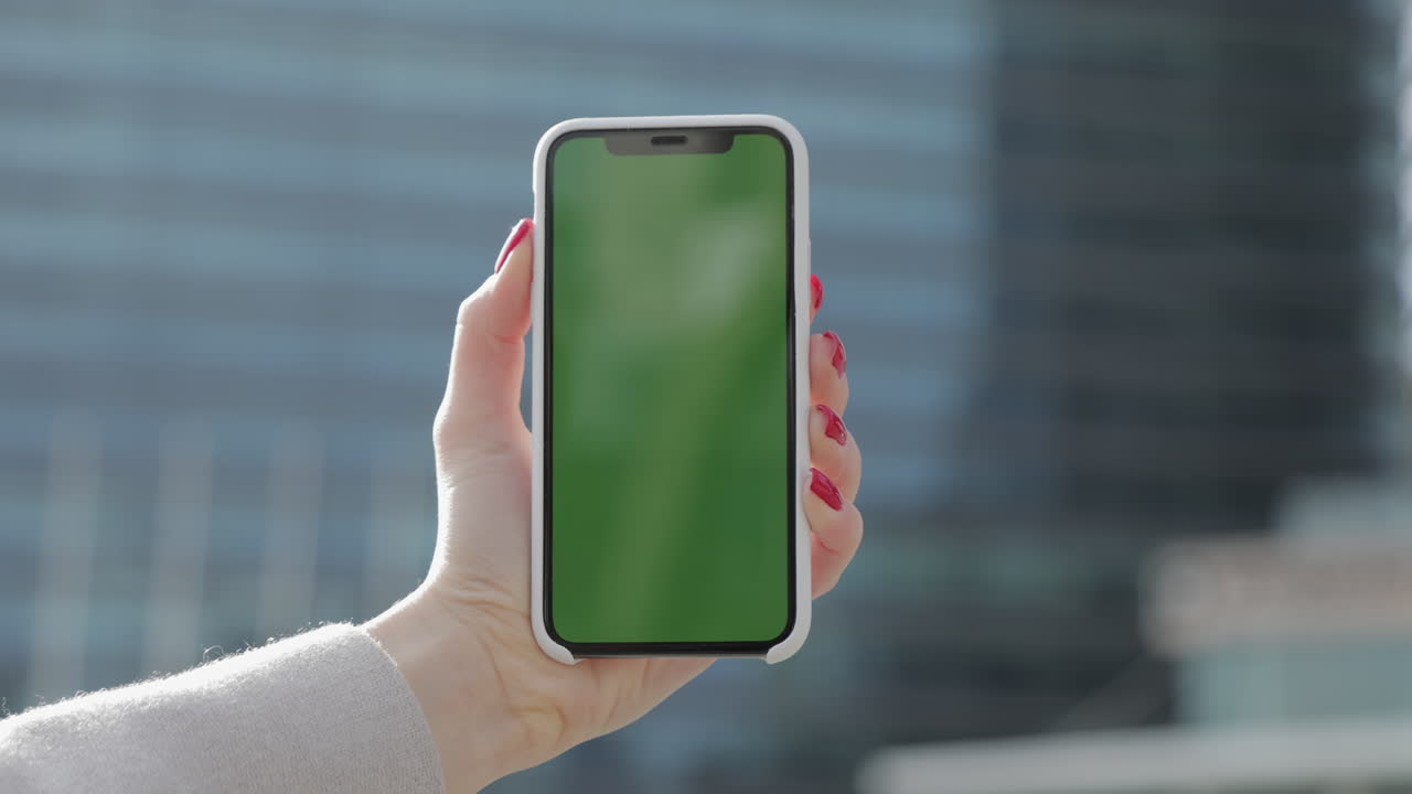 mujer sosteniendo un teléfono inteligente con una pantalla verde