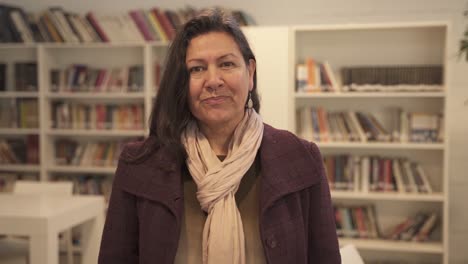 pretty middle aged woman smiling at camera standing inside library,close up shot