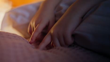 little girl touches covering by fingers before going sleep