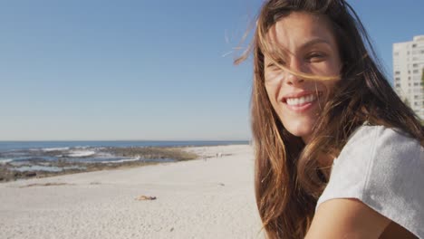 Mujer-Joven-Sentada-En-Una-Playa-Sonriendo