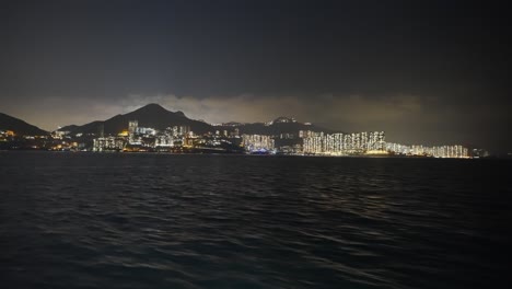 Aufnahme-Von-Einem-Boot-Aus,-Das-Mitten-In-Der-Nacht-Links-Von-Einer-Urbanisierten-Insel-Fährt-3