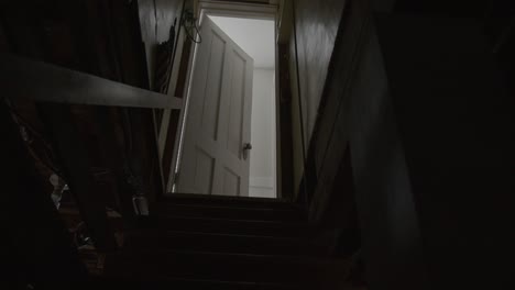 wide tilt up shot of a dark and creepy basement staircase