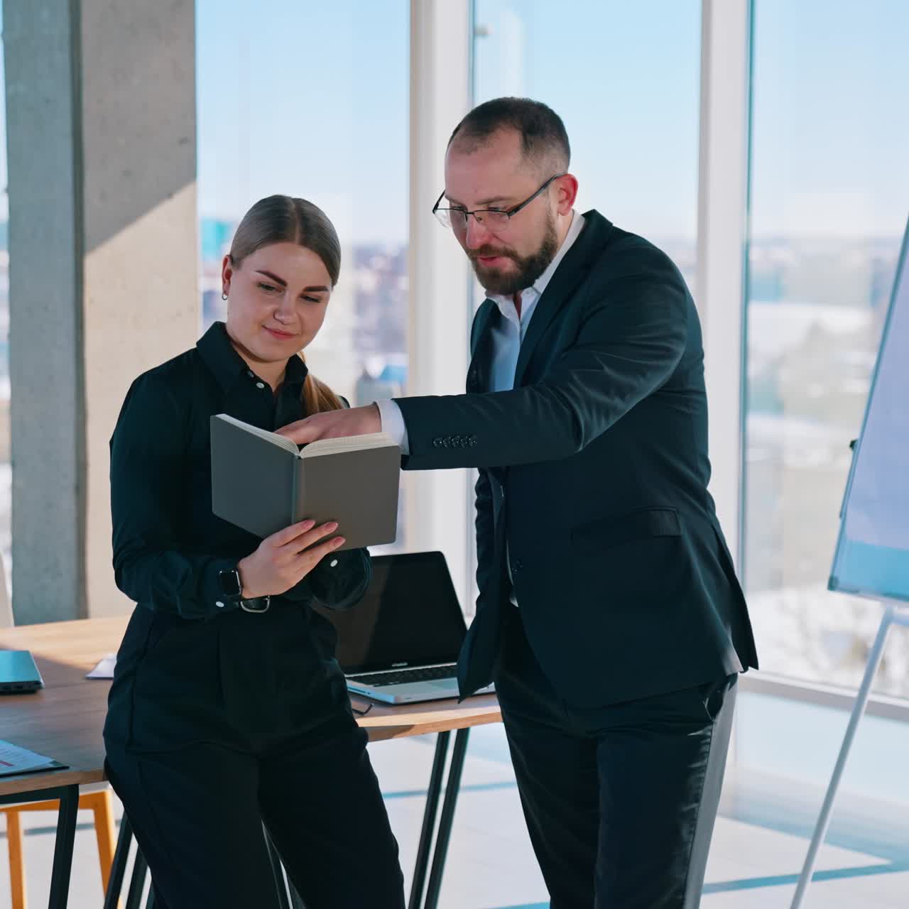 Friendly business workers indoors. Man in suit and beautiful woman having a conversation about business in modern office