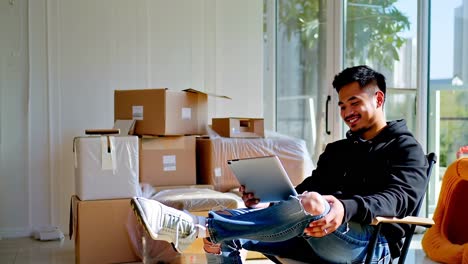 man using tablet amidst moving boxes in new home