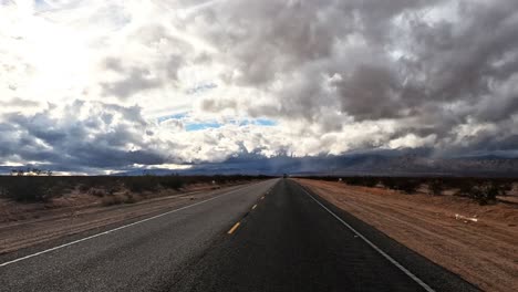 dark ominous clouds above a lonely highway through the mojave desert - driver point of view hyper lapse