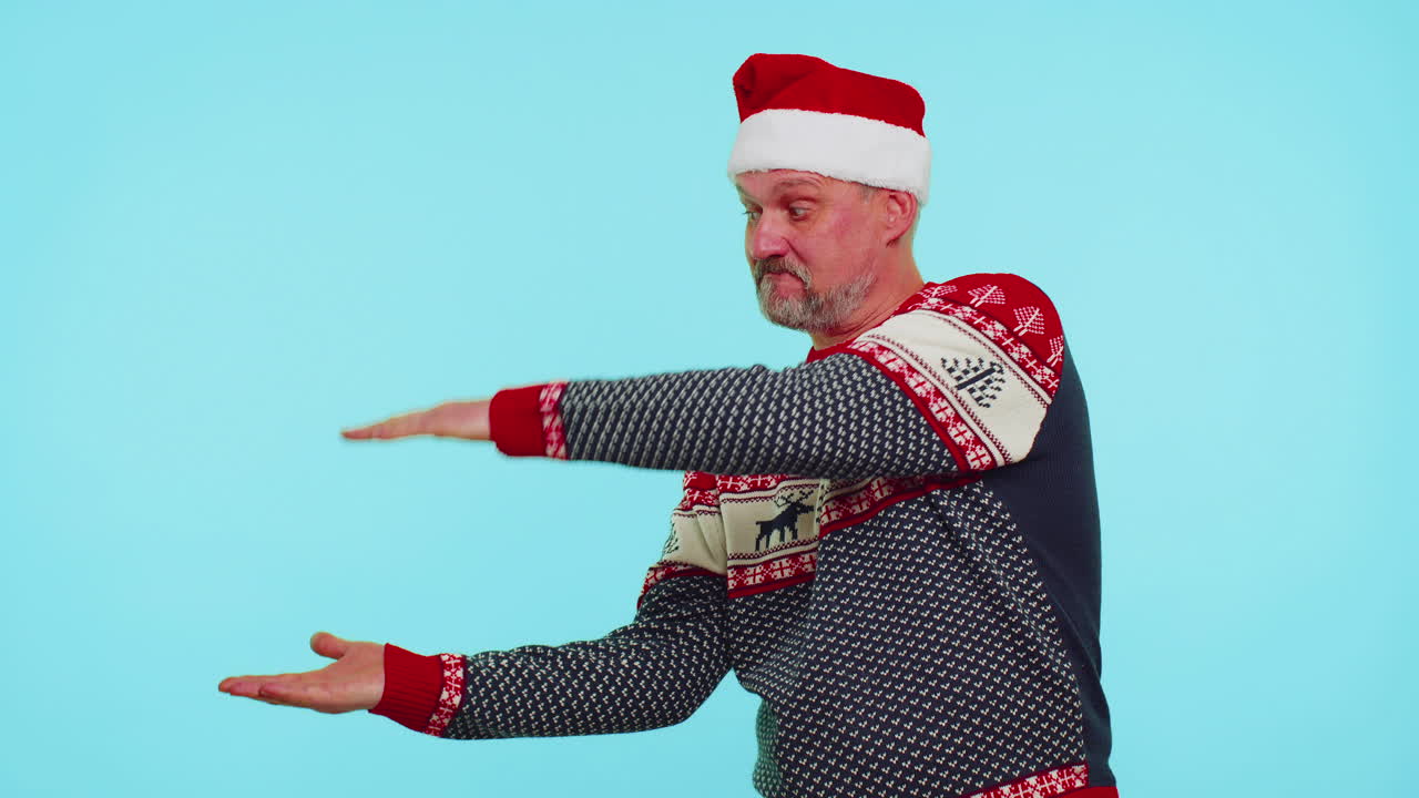 hombre con suéter rojo papá noel mostrando los pulgares hacia arriba y señalando un lugar vacío, área de publicidad