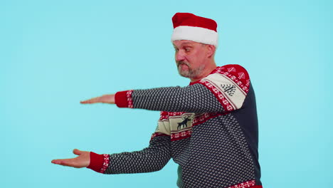 Man-in-red-sweater-Santa-Christmas-showing-thumbs-up-and-pointing-empty-place,-advertising-area