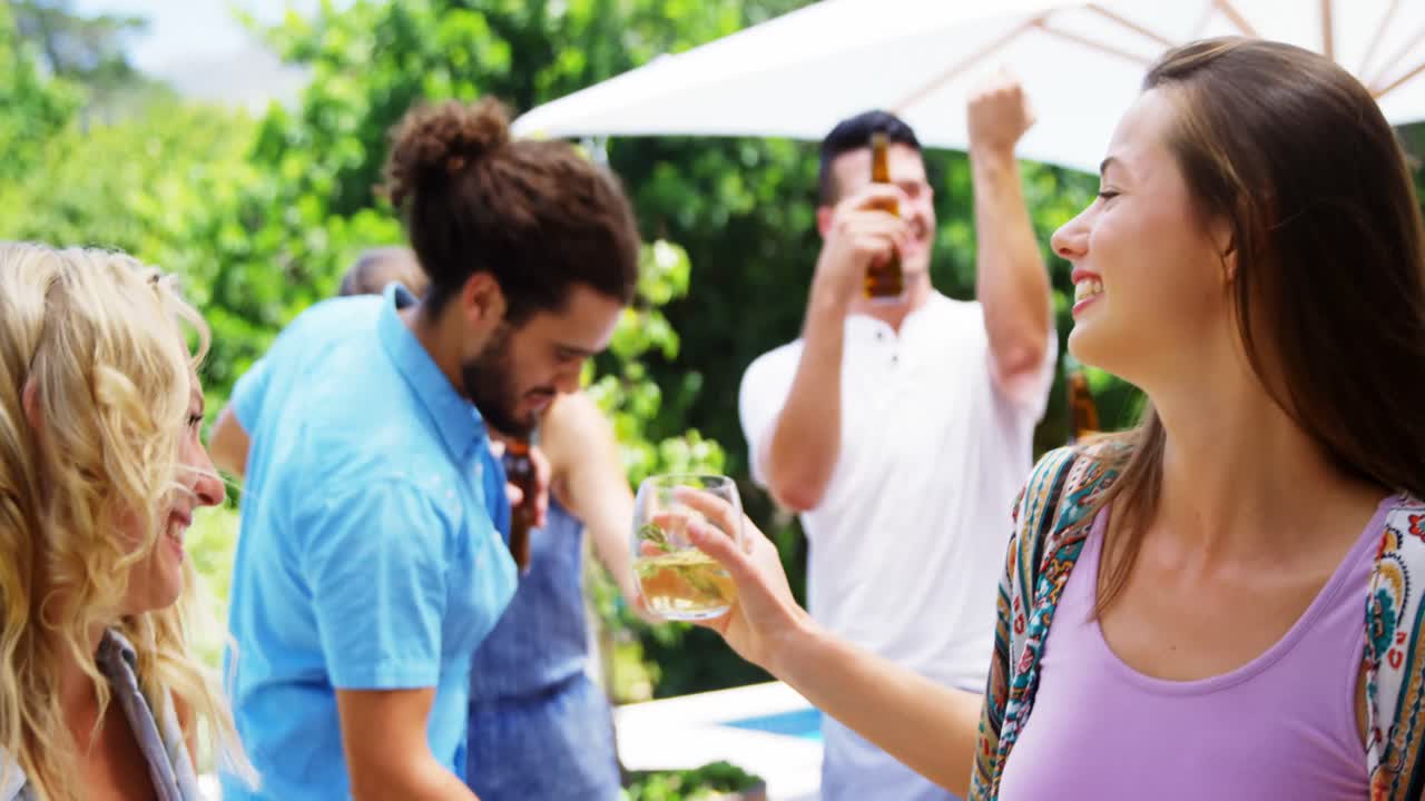 grupo de amigos bailando mientras toman bebidas en una fiesta de barbacoa al aire libre