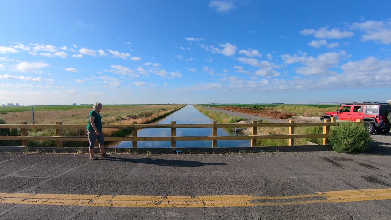 관개 운하 를 가로질러 다리 를 고 있는 여자