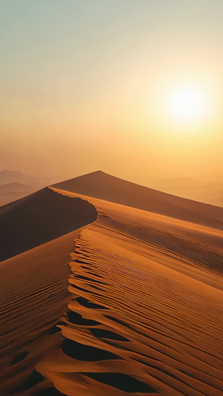 Vertical video: Gliding camera following dune crest at sand sea, revealing rippled flanks, low sun