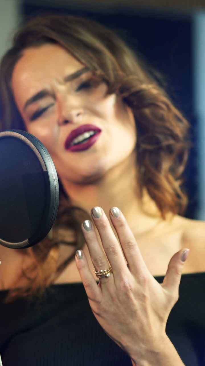 young singer is singing and recording a song in the audio studio on a blue background. Close-up Vertical video