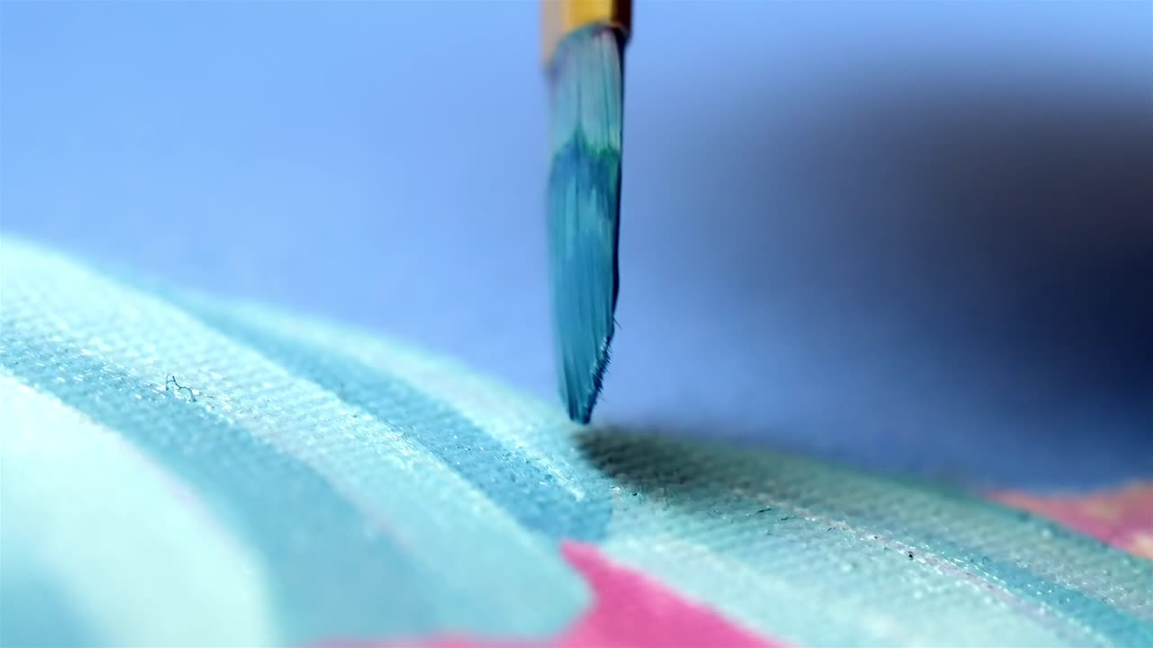 Primo piano estremo di un piccolo pennello che crea una pennellata blu su tela.