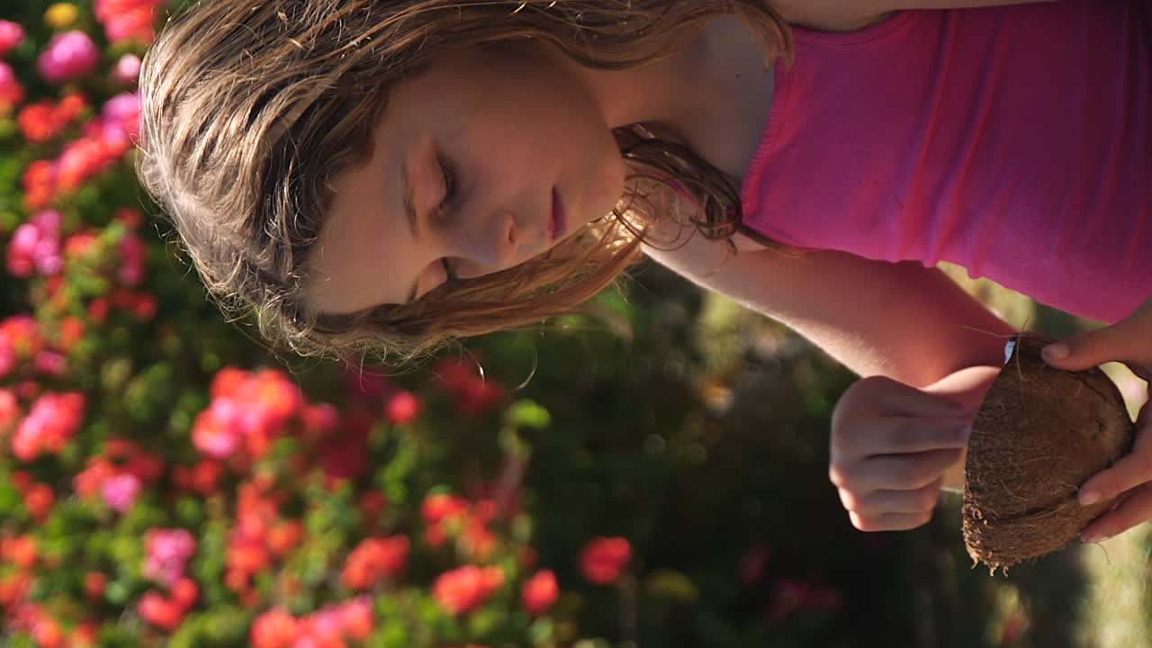chica preadolescente en un entorno tropical comiendo la carne o el endosperma de un coco - vertical de cerca