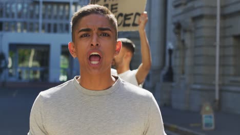 two mixed race men on a protest march holding placards raising hands and shouting