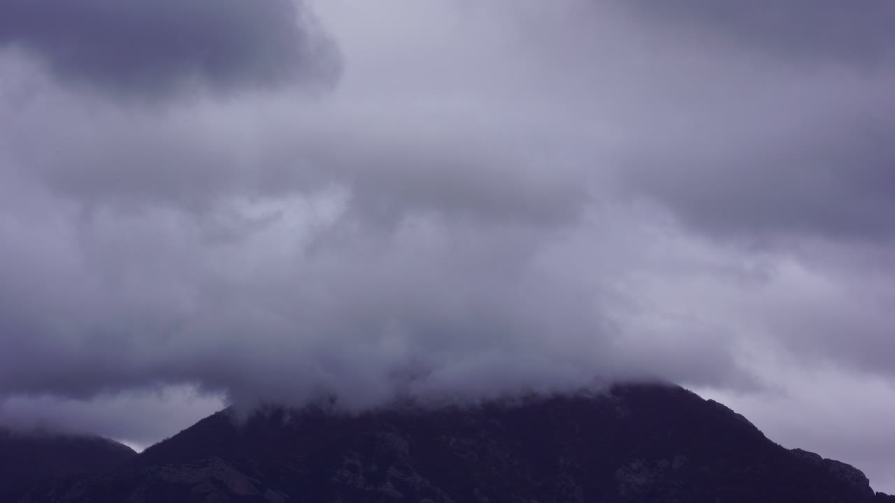 겨울에 높은 산을 덮고 있는 먹구름, 연기가 사면에 스며든다