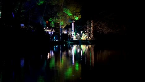 Concierto-En-Vivo-En-Una-Noche-De-Primavera-Cerca-Del-Lago-En-El-Parque-De-La-Ciudad-Entre-Las-Luces-Reflejadas-En-El-Agua