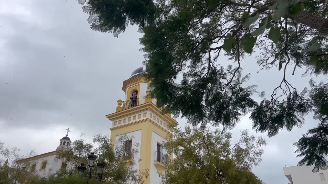 vista reveladora de la torre de la iglesia en españa, se eleva majestuosamente contra el telón de fondo de un cielo temperamental y nublado durante un día de viento