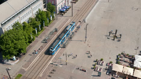 Descending-and-tilt-up-footage-of-tram-leaving-tram-stop-at-Neue-Markt-square.-Public-transportation-in-city