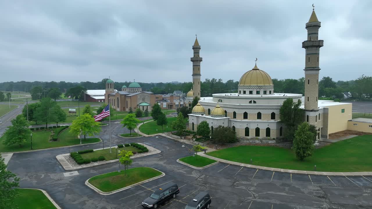 Aerial approaching shot of Islamic Center of American with forest and dense clouds at sky in backdrop - Establishing drone shot