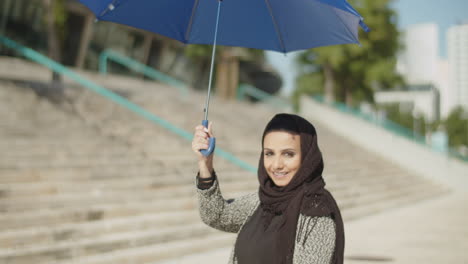 Junge-Muslimische-Frau-Im-Hijab,-Die-Einen-Regenschirm-über-Ihrem-Kopf-Hält.