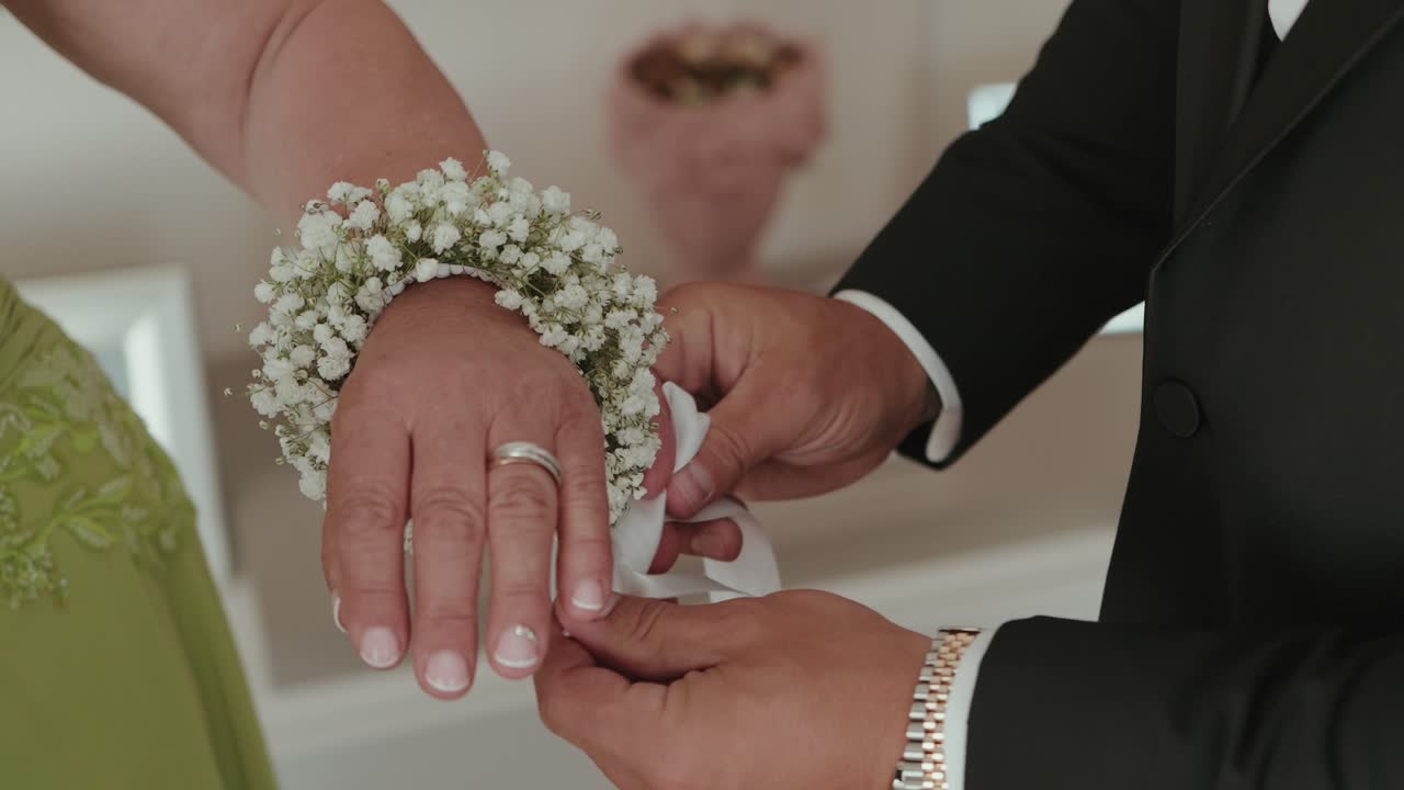 Close up of a floral bracelet being adjusted on a wrist with delicate white flowers