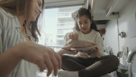 mother and little daughter doing the dishes at home