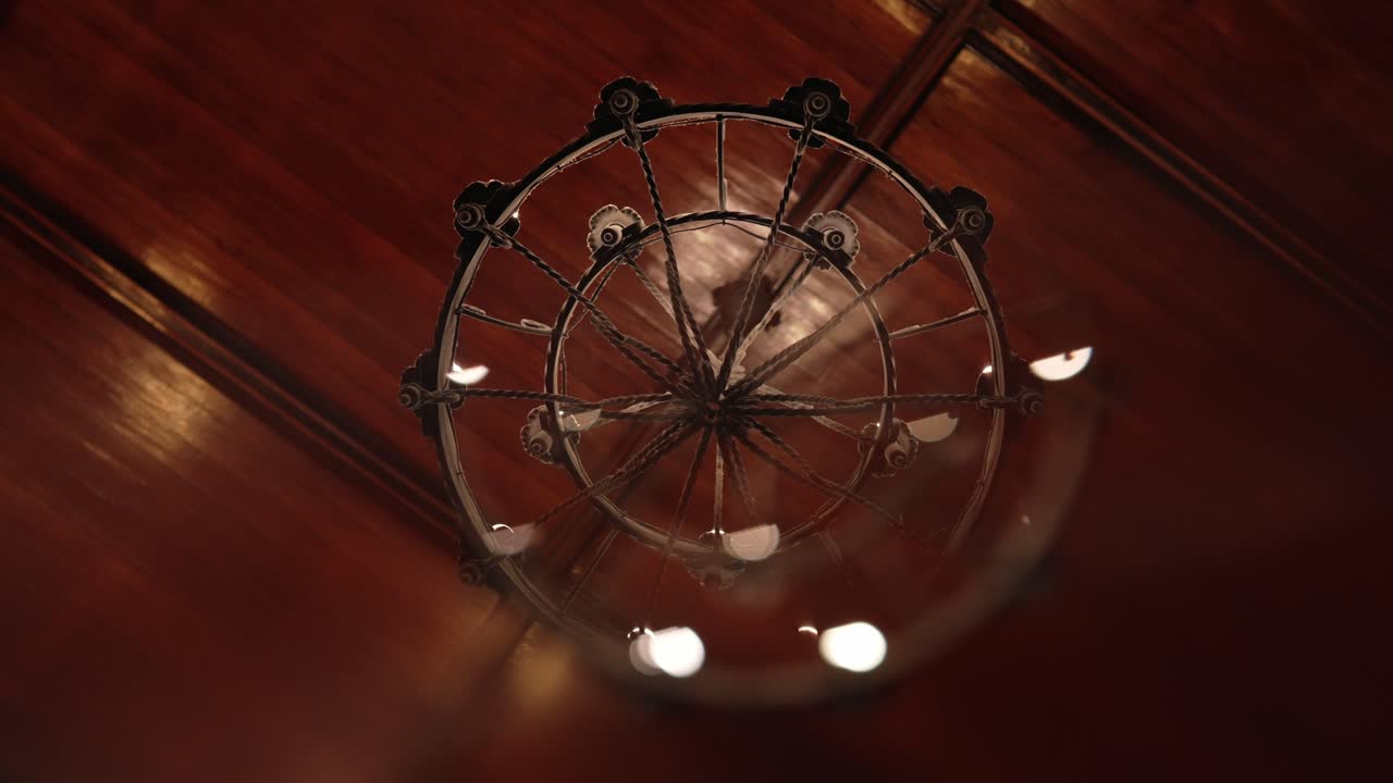 ornate chandelier viewed from below with warm wooden ceiling