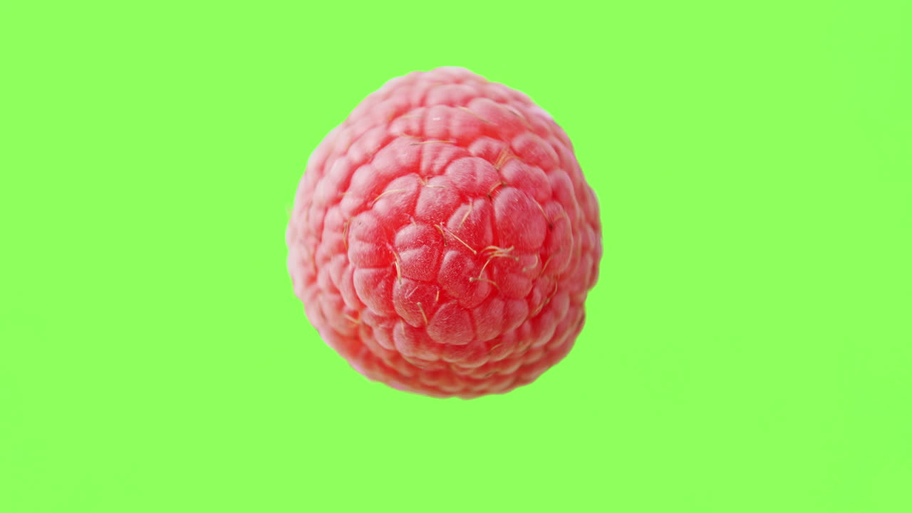 A raspberry rotating clockwise in the air before a green background