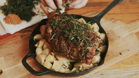 garnishing green herb spices on a grilled lamb served leg