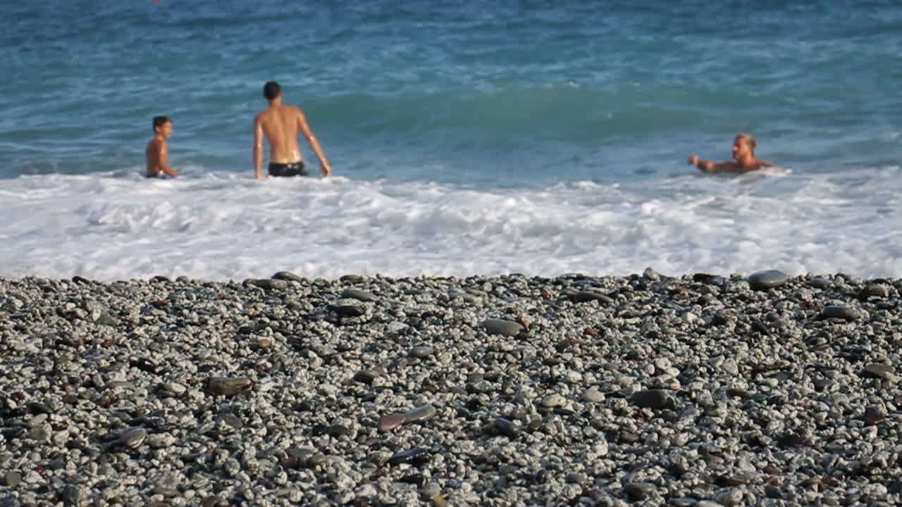 People swimming in the sea on a pebble beach