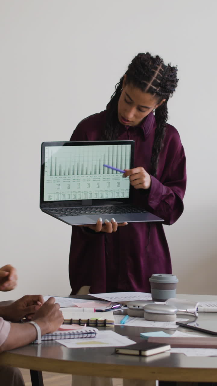 Woman presenting data on a laptop in a business meeting
