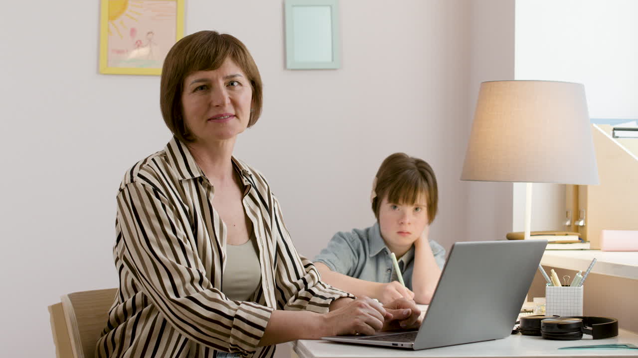 Woman looking at camera while her daughter studies