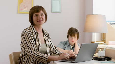 woman looking at camera while her daughter studies