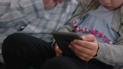 gelukkige grootvader toont klein meisje hoe je een smartphone moet gebruiken leert nieuwsgierige kleindochter moderne technologie intelligent kind leert mobiele telefoon zit met grootvader op de bank