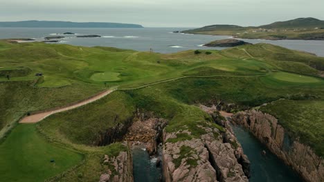 drone orbit to reveal stunning coastline of ireland links golf course with rolling green fairways and cliffs down to ocean