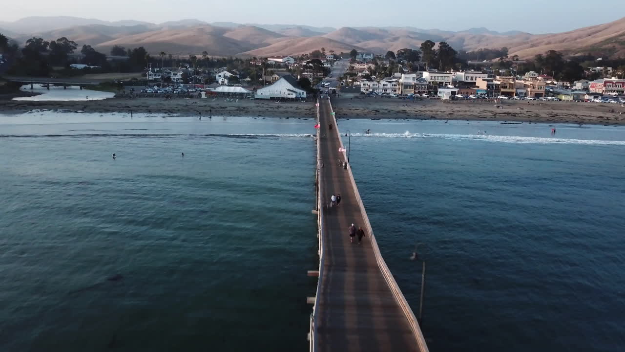 la gente camina en un largo muelle desde un pueblo tranquilo