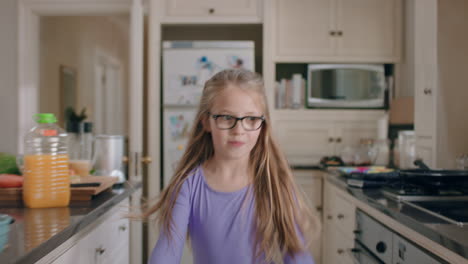 happy ballerina girl dancing in kitchen having fun practicing ballet dance moves wearing purple tutu at home