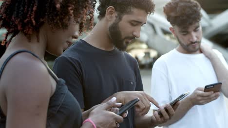 group of young people using devices on street