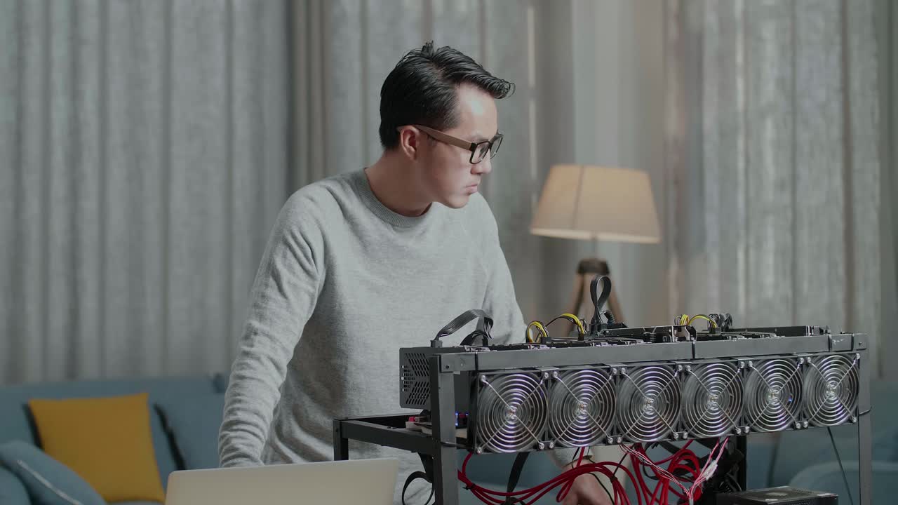 Asian Man Wearing Glasses Looking At The Cryptocurrency Mining While Working With A Laptop