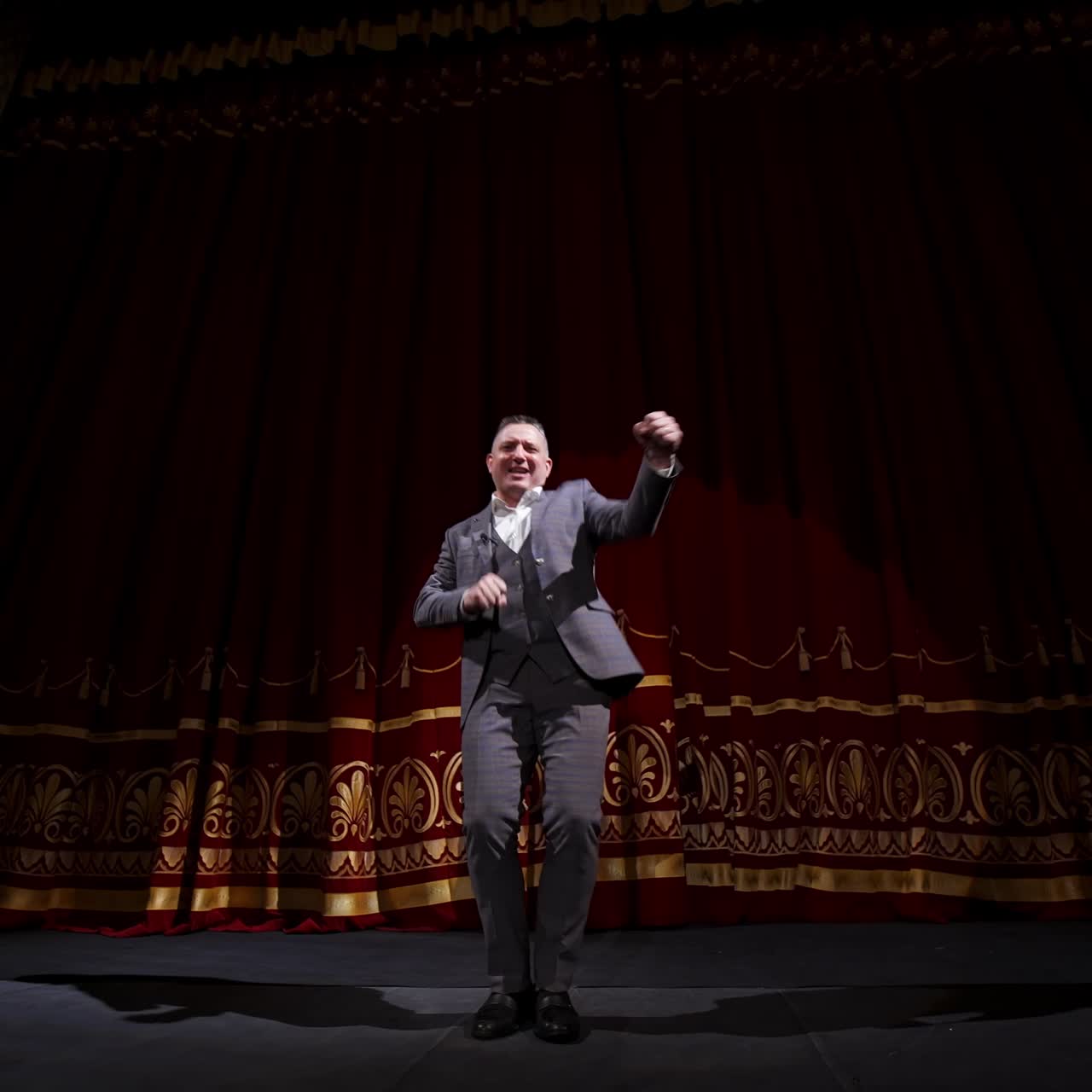 Portrait of a comedian talking. Cheerful actor in suit telling funny stories and gesticulating a lot. Joyful man performing on stage