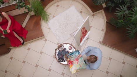 el artista agrega agua para pintar en el dibujo de modelo en vivo. el pintor profesional hace una sombra rosa suave para dibujar el retrato de la mujer en la galería. el hombre crea una imagen