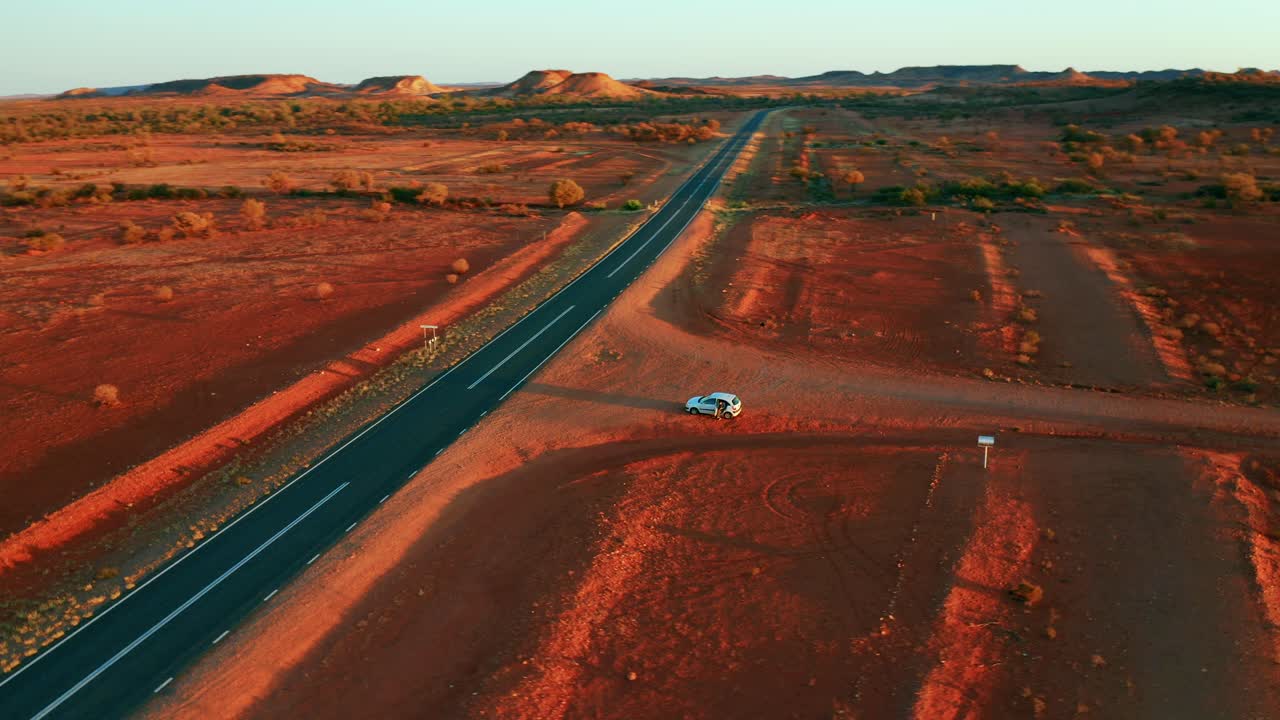 coche blanco estacionado en el desierto de color rojo cerca de la carretera asfaltada en alice springs, australia