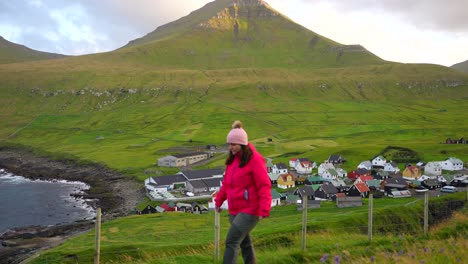 mujer caminando cerca de la hermosa aldea gjogv y las montañas en eysturoy, islas feroe