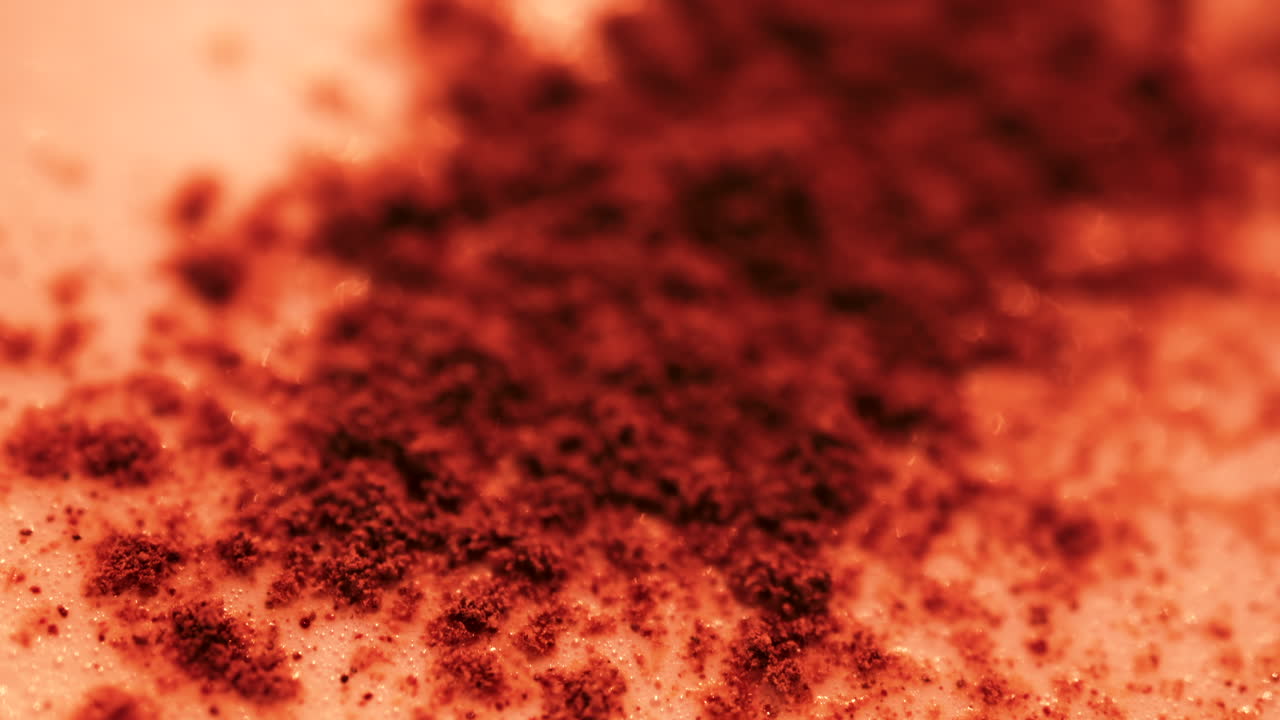 Close up of cocoa sprinkled over frothy milk, with rich warm tones