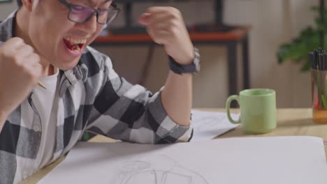 close up of asian male celebrating success working on a car design sketch on table in the studio