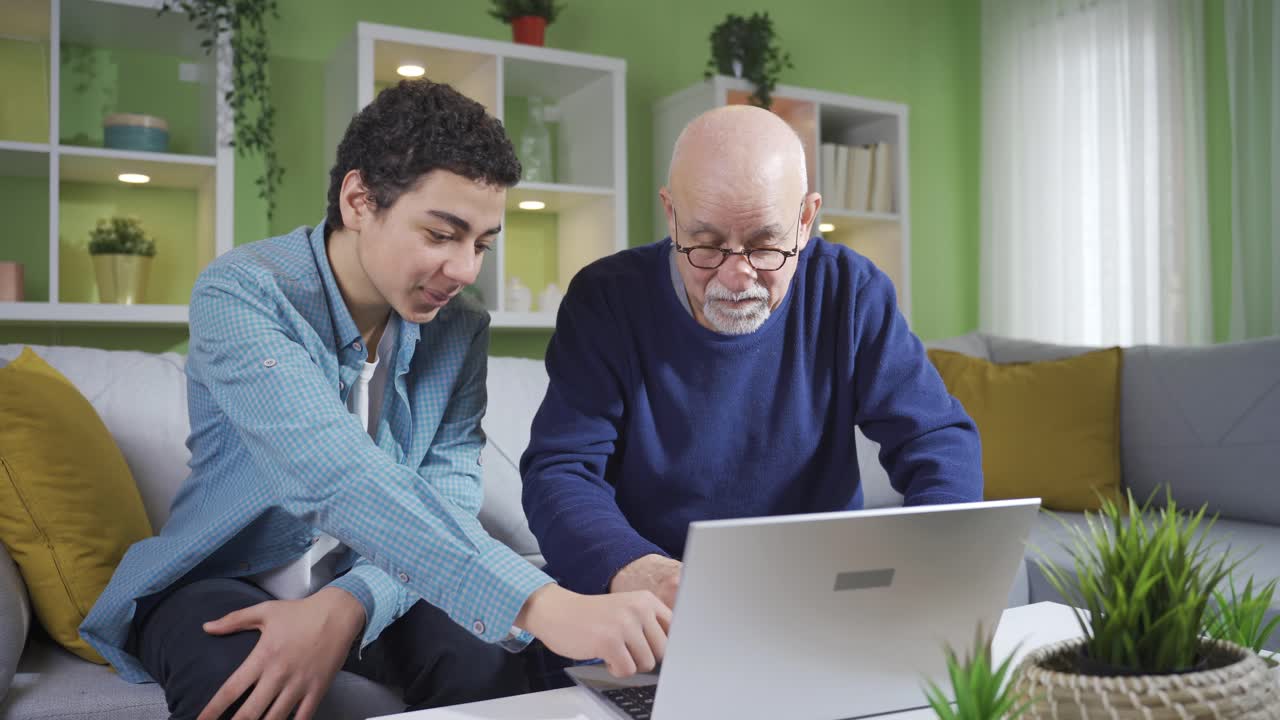 The grandson teaches his grandfather, who does not know how to use a laptop, to use a laptop.