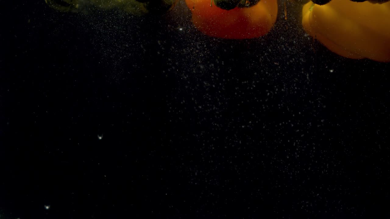 coles de bruselas y pimentón cayendo en el agua con un salpico y burbujas